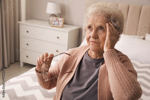 Senior woman with headache in bedroom at home