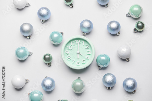 Composition with alarm clock and Christmas balls on light background
