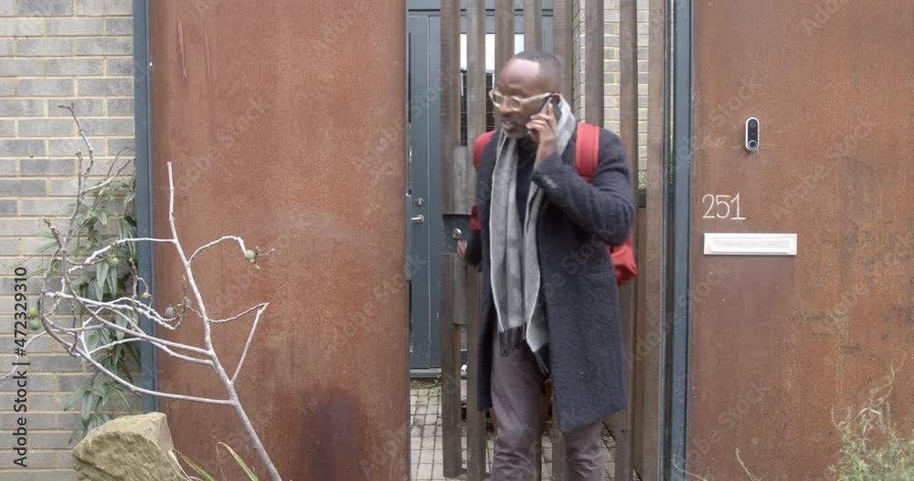 Black male leaving home talking on smart phone Black male leaving home talking on smart phone