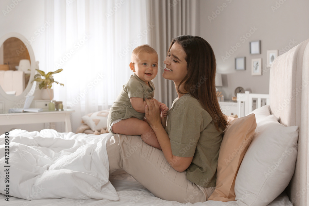 Happy young mother with her cute baby on bed at home Happy young mother with her cute baby on bed at home
