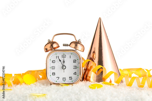 Christmas composition with alarm clock, party hat and serpentine on snow against white background