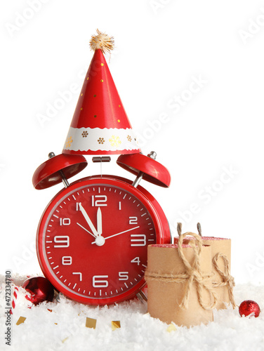 Beautiful composition with alarm clock, party hat and candles on snow against white background