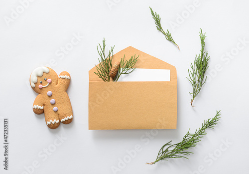 Composition with envelope, card, coniferous branches and cookie on white background