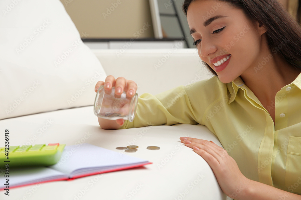 Young woman counting money near sofa at home Young woman counting money near sofa at home