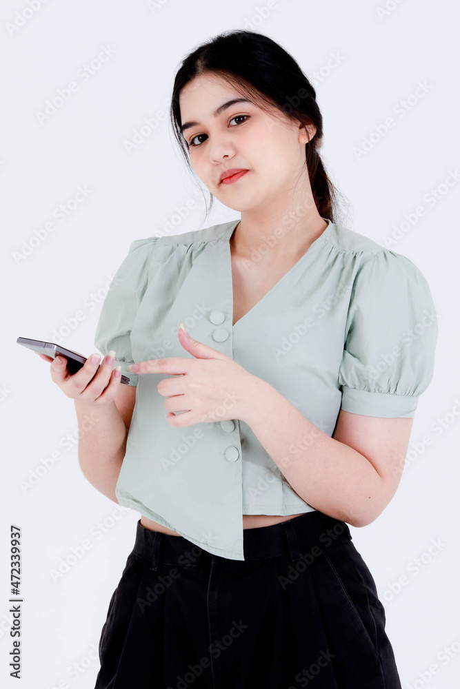 Studio shot of Asian young teen female model with ponytail hair wear dental care teeth braces and crop top outfit standing waving hand greeting say hi on smartphone video call on white background Studio shot of Asian young teen female model with ponytail hair wear dental care teeth braces and crop top outfit standing waving hand greeting say hi on smartphone video call on white background