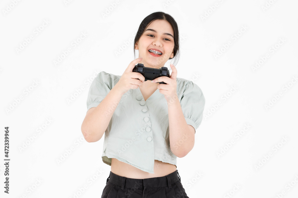 Portrait closeup studio shot of Asian young happy teen female model with ponytail hairstyle wearing dental care teeth braces and casual crop top outfit hold joystick playing game on white background Portrait closeup studio shot of Asian young happy teen female model with ponytail hairstyle wearing dental care teeth braces and casual crop top outfit hold joystick playing game on white background