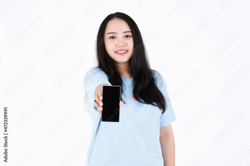 Studio shot of Asian chubby plump long black hair female model in blue casual t shirt and smiling holding smartphone on white background Studio shot of Asian chubby plump long black hair female model in blue casual t shirt and smiling holding smartphone on white background