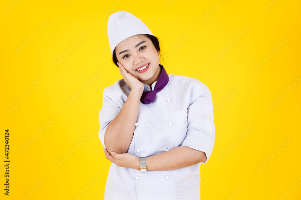 Portrait studio shot of Asian professional successful smart confident hotel restaurant female executive chef in white cooking uniform standing smiling look at camera crossed arms on yellow background