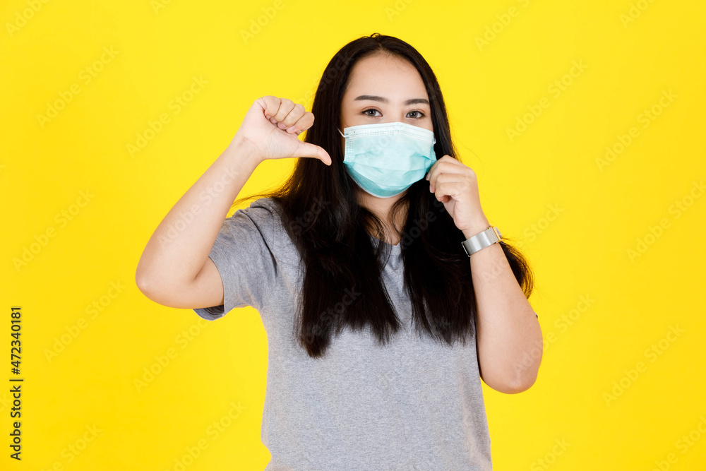 Portrait studio shot of Asian young chubby plump long black hair female model in gray casual outfit and face mask standing hold hands on face shocked excited amazed surprised on yellow background Portrait studio shot of Asian young chubby plump long black hair female model in gray casual outfit and face mask standing hold hands on face shocked excited amazed surprised on yellow background