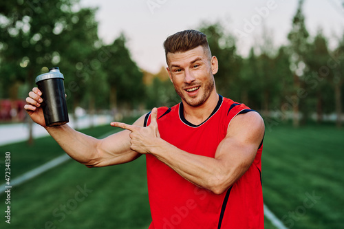 Cheerful sporty man in the park on green grass doing exercises