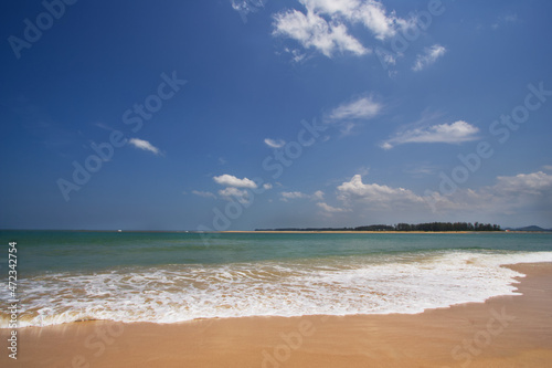 A scenery of beach with waves from south of Thailand in strong daylight with blue sky and white cloud, clean soft sand.