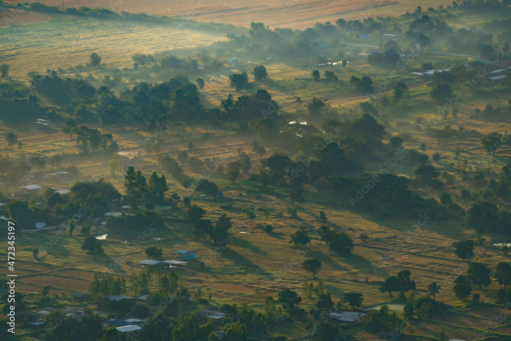 Morning sunlight shine through misty to the hillside village with farmland, View from 