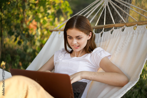 women outdoors lies in a hammock with a laptop freelance internet © VICHIZH