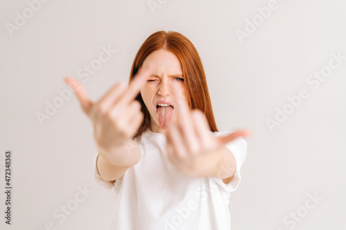 Foto Portrait of excited young woman showing middle fingers on both arms, gesture of disrespect and hate, doing bad expression
