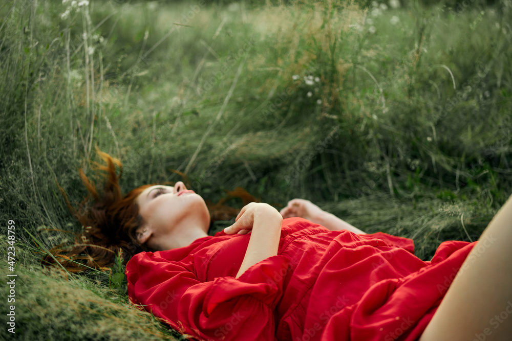pretty woman in red dress lies on the grass in the field nature fresh air pretty woman in red dress lies on the grass in the field nature fresh air