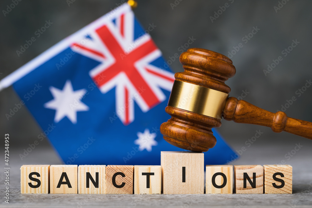 Judge gavel, wooden cubes with text and the Australian flag on an abstract background, a concept on the theme of sanctions in Australia