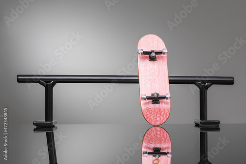 Fotografi Small fingerboard and black metal railing on a gradient background