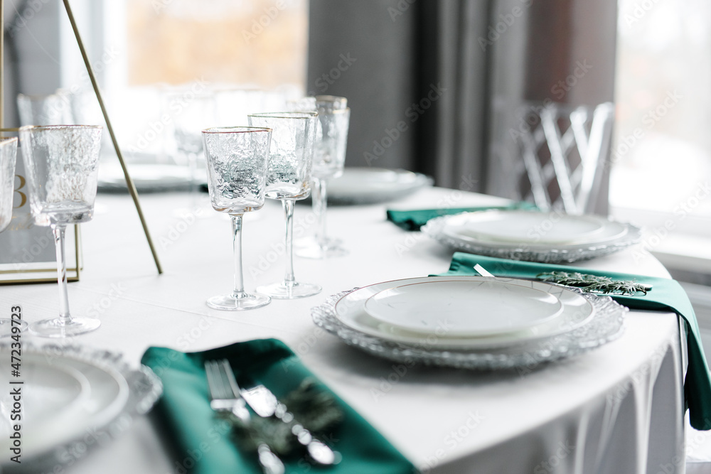 Beautiful festive table setting with napkins of different colors. A luxurious dining set with cutlery, napkin, dishes and covered with a tablecloth in the restaurant. Gold plates and crystal glasses. Beautiful festive table setting with napkins of different colors. A luxurious dining set with cutlery, napkin, dishes and covered with a tablecloth in the restaurant. Gold plates and crystal glasses.