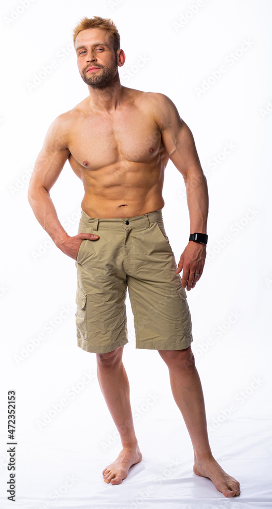 muscular man in shorts posing, shows, straining muscles. gray background muscular man in shorts posing, shows, straining muscles. gray background