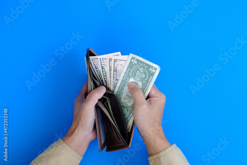 Hand holding banknote with money concept on blue background, finance and banking