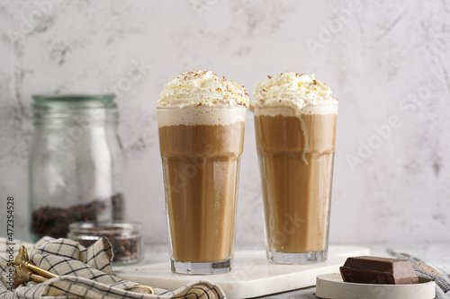 Two tall glasses with cold coffee drink frappe - iced cappuccino with whipped cream on a marble board photo