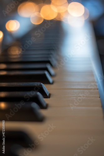 piano keys with beautiful highlights from Christmas lamps with rich bokeh and shallow depth of field