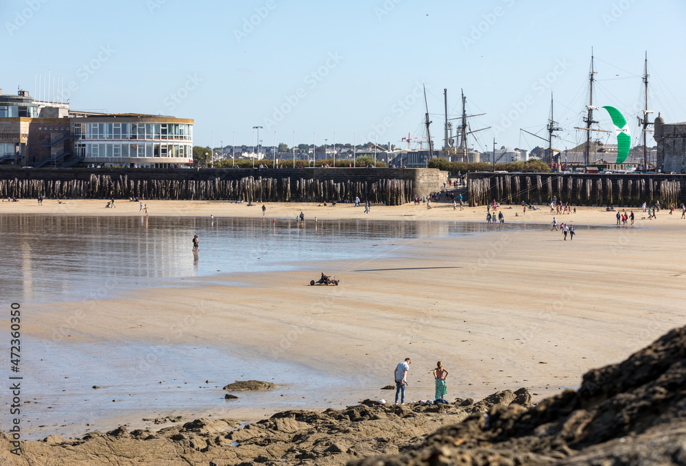 Naklejka premium Romantic walk of people before sunset on the picturesque beach of Saint Malo. Brittany, France
