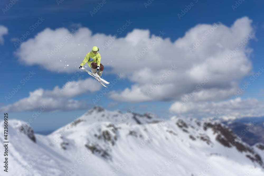 A jumping skier in the mountains. Mountain ski, winter extreme sport.