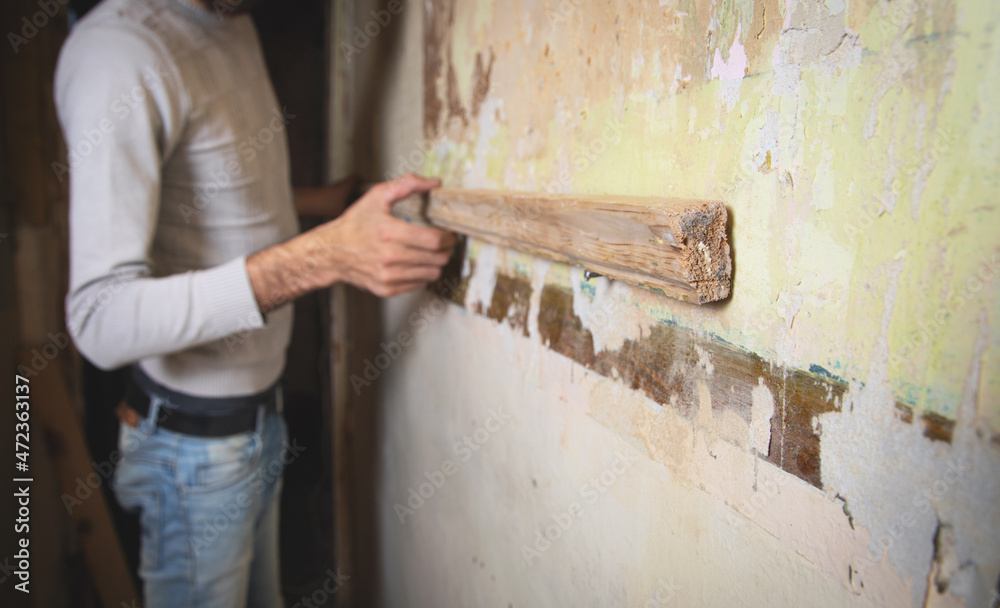 Worker installing wooden plank to wall. Worker installing wooden plank to wall.
