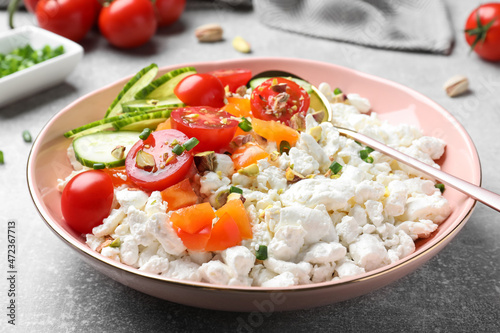 Delicious cottage cheese with vegetables served for breakfast on light grey table, closeup