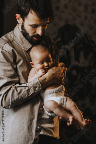 Caucasian father kissing newborn baby. Parent holding rocking child daughter son in hands. Authentic lifestyle parenting fatherhood moment. Single dad family home life. Toned