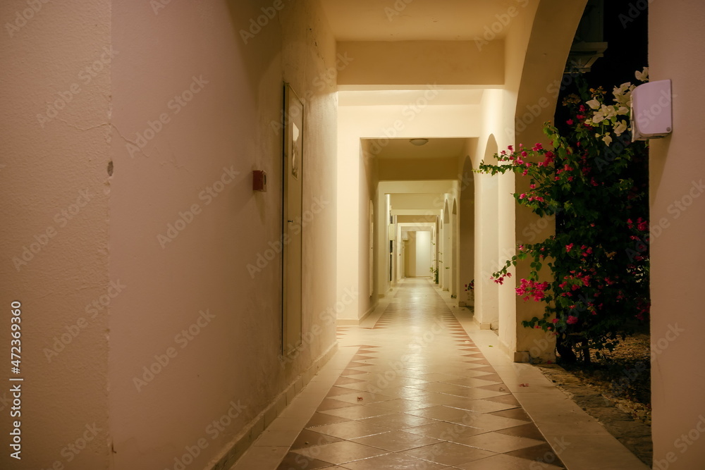 The corridor and arches of the white building is illuminated by