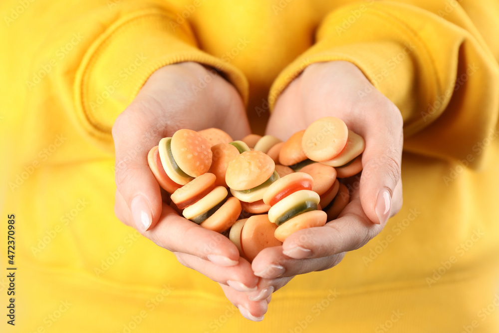 Woman holding handful of delicious gummy burger shaped candies, closeup Woman holding handful of delicious gummy burger shaped candies, closeup