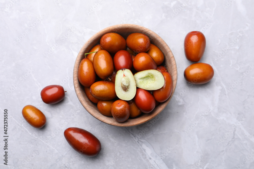 Fresh Ziziphus jujuba fruits with bowl on light table, flat lay Fresh Ziziphus jujuba fruits with bowl on light table, flat lay