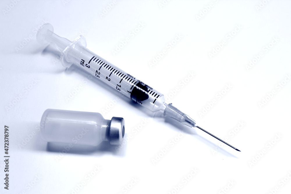 Vial of drugs or vaccine and 3 ml plastic syringe with needle isolated on the white background, blue tone color Vial of drugs or vaccine and 3 ml plastic syringe with needle isolated on the white background, blue tone color