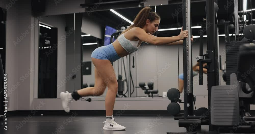 Woman make exercise on gym training apparatus for training legs and buttocks