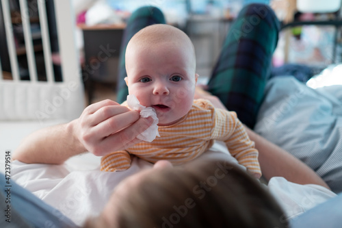 Bilde på lerret Young fatherwipes drool with white paper handkerchief of his newborn baby girl in bed