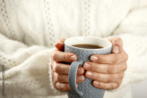 A hot Christmas drink in the hands of a senior on Christmas Eve 