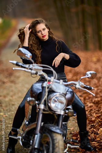 A beautiful woman with long hair on a chopper motorcycle in autumn landscape. © czamfir