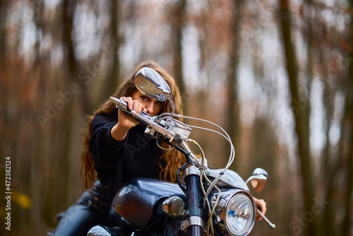 A beautiful woman with long hair on a chopper motorcycle in autumn landscape.