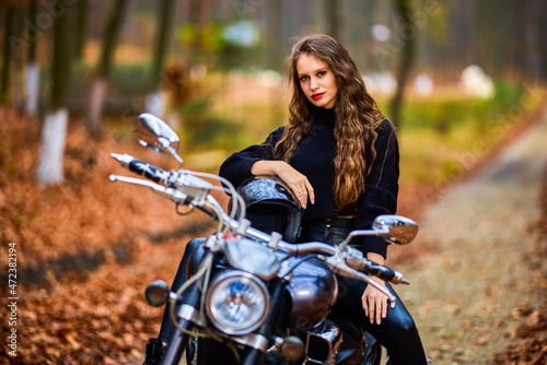 A beautiful woman with long hair on a chopper motorcycle in autumn landscape. © czamfir