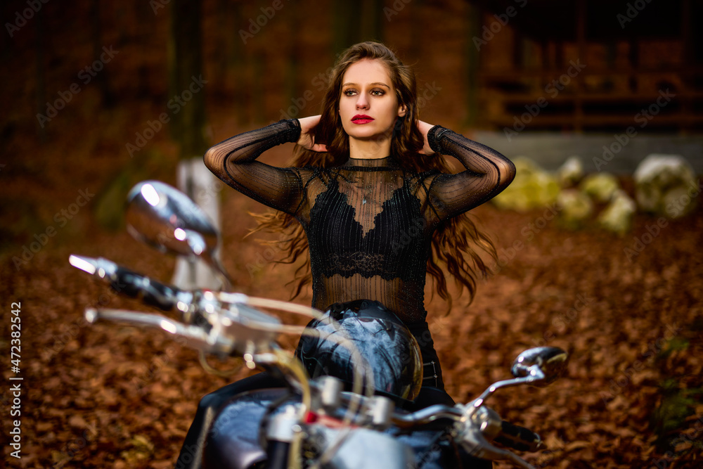 Obraz premium A beautiful woman with long hair on a chopper motorcycle in autumn landscape.