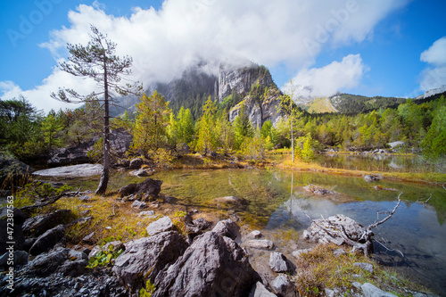 A quiet alps landscape with a pond, pine trees and a mountain top in the Swiss alps. in autumn 