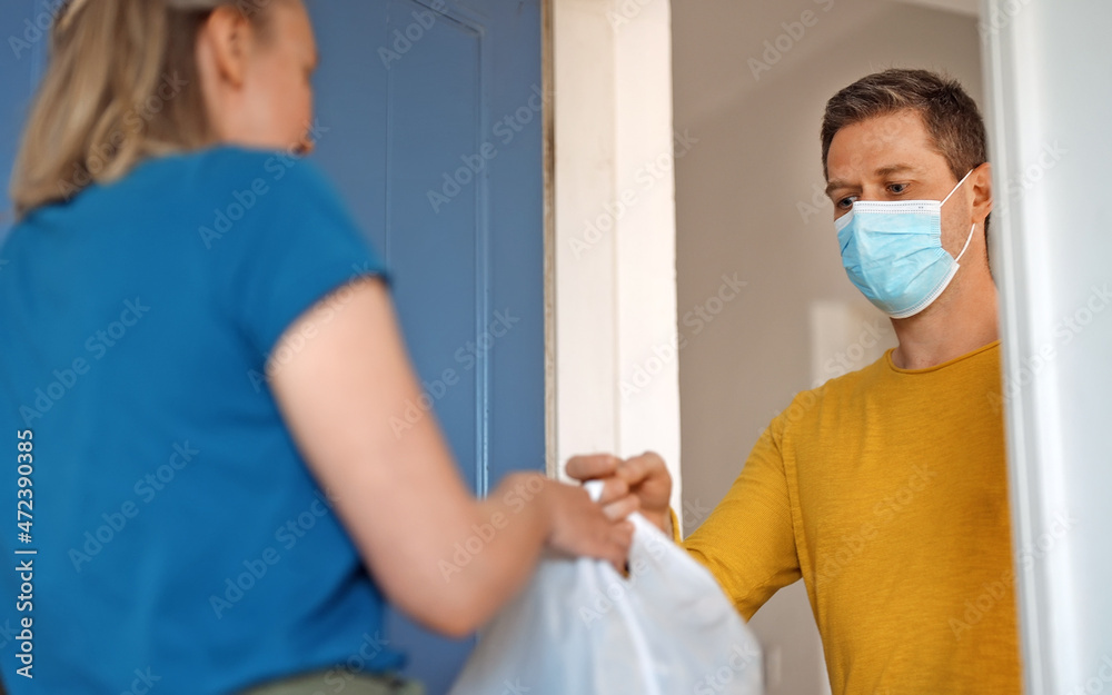 Fototapeta premium Masked man delivers food during pandemic.