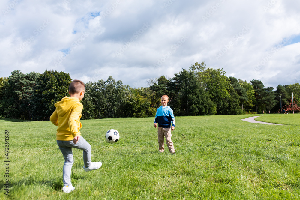 childhood, leisure games and people concept - happy little boy with ball playing soccer at summer park childhood, leisure games and people concept - happy little boy with ball playing soccer at summer park