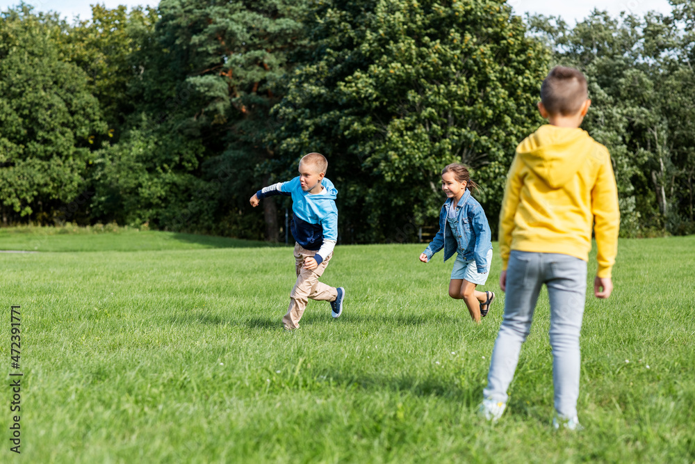 childhood, leisure and people concept - group of happy kids playing tag game and running at park childhood, leisure and people concept - group of happy kids playing tag game and running at park