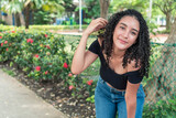 Portrait of curly-haired young Latina in the park in the morning
