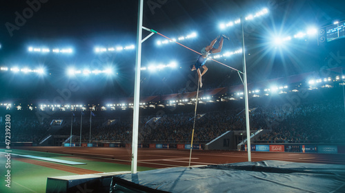 Pole Vault Jumping: Professional Male Athlete on World Championship Successfully Jumping with Pole over Bar. Shot of Competition on Big Stadium with Sports Achievement Experience