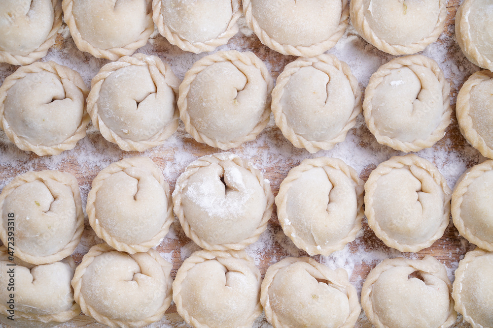 Meat or vegeterian dumplings, pelmeni on a wooden board. Russian national food. Close up top view.