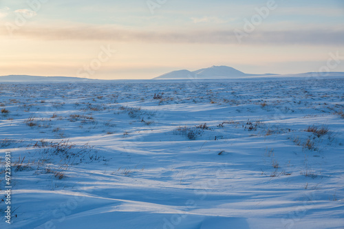 View of the snow-covered tundra and snow-capped mountains. Winter arctic landscape. Cold frosty winter weather. Arctic desert. Northern nature of polar Siberia and Chukotka. The Far North of Russia.